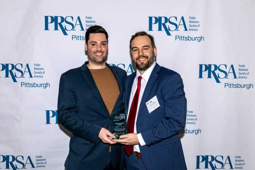 Account Director William Berry & Marketing Manager Devon Moore holding PRSA Renaissance Award for Digital Marketing Campaign